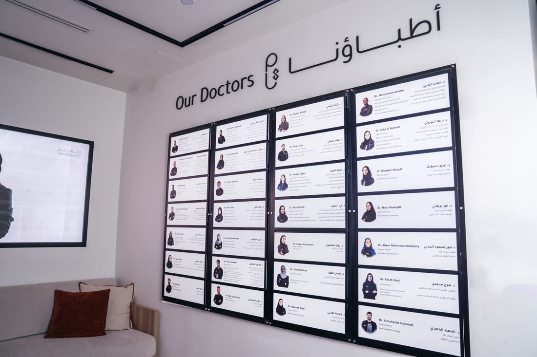 A wall board at Tam Dental headed Our Doctors, listing the consultants with their names and specialties.